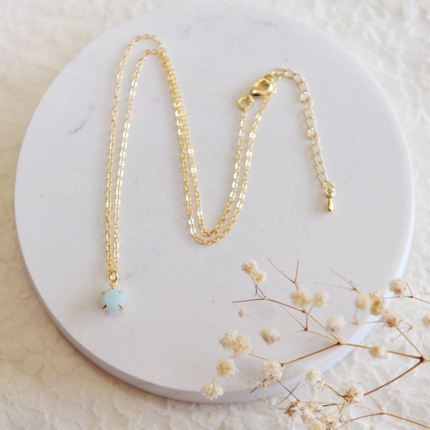 Gold necklace with a blue amazonite stone on a white stone backdrop