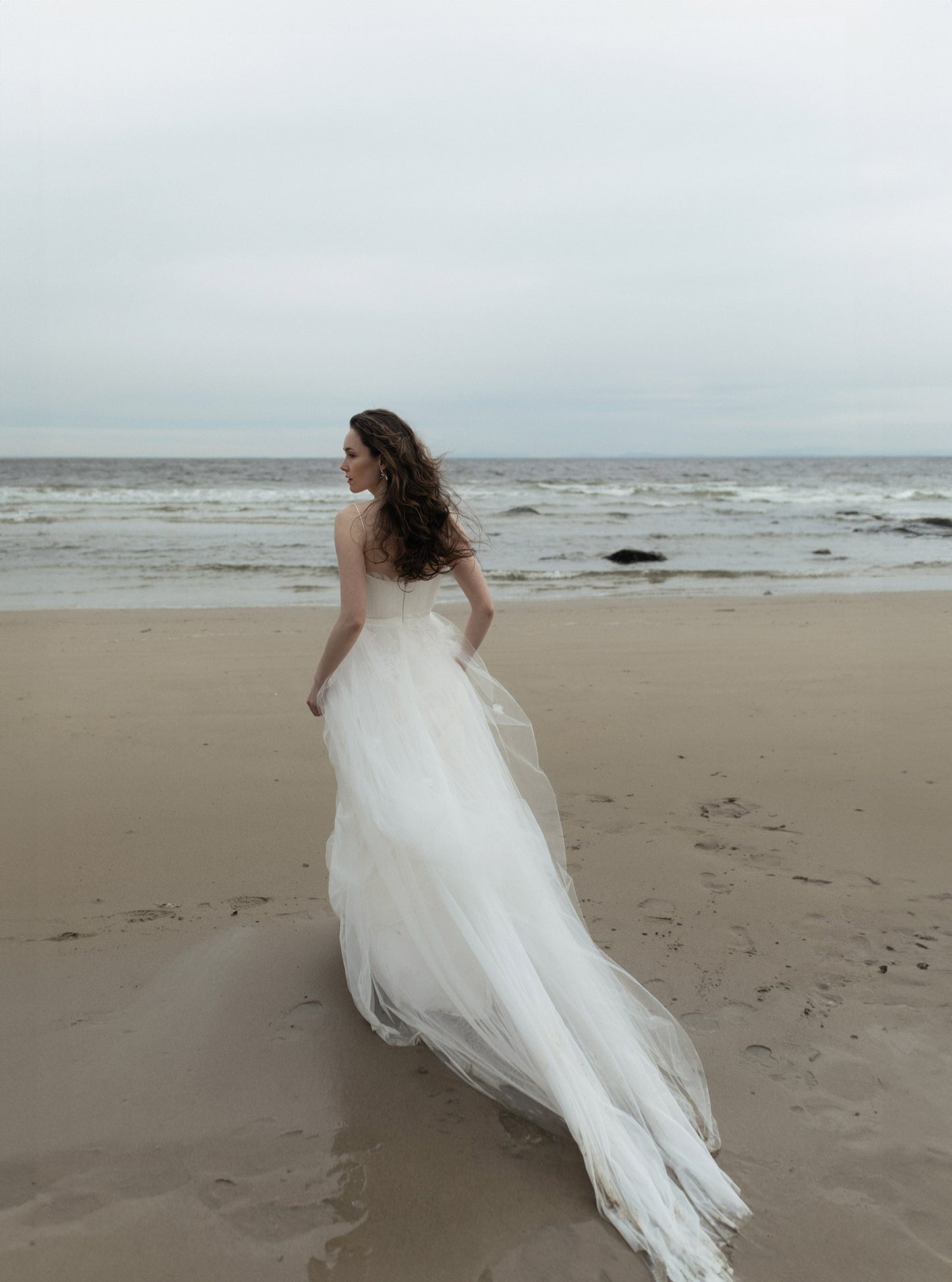 Woman in a white wedding dress standing on a beach