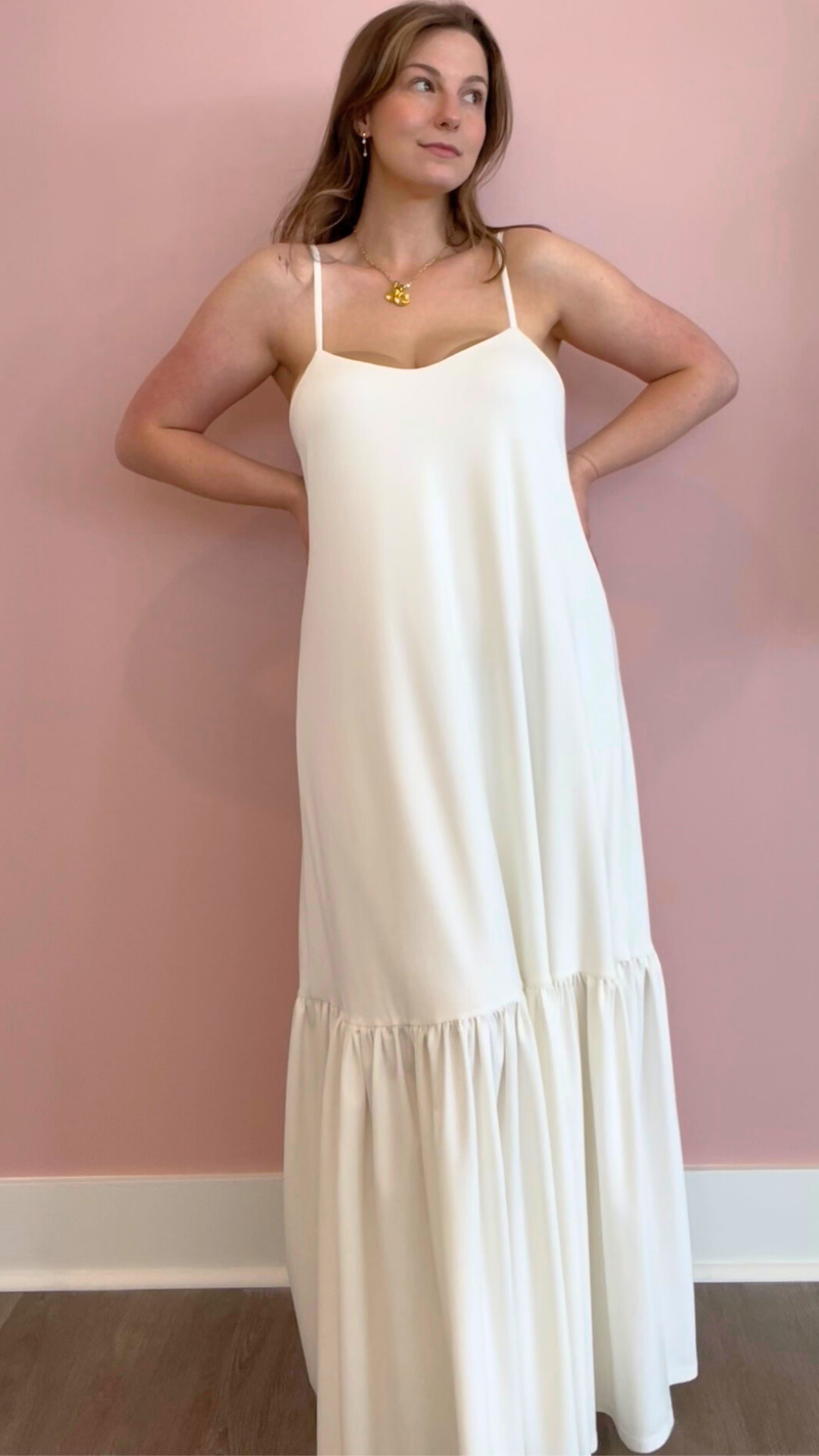 Woman wearing a white slip dress against a pink wall