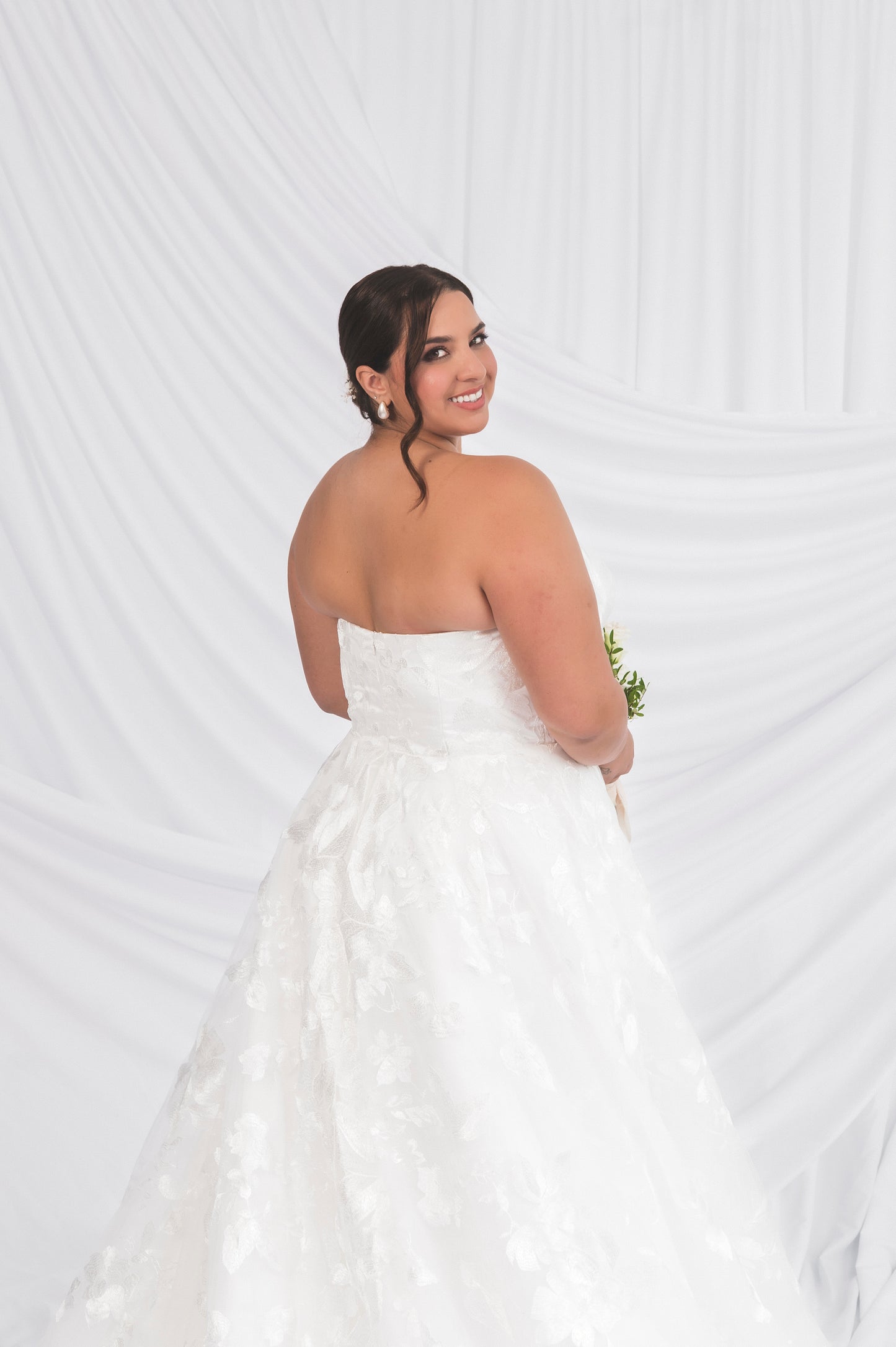 Canadian Made Wedding Dress against a white background draped, stragith across modest backline with a classic lace full skirt