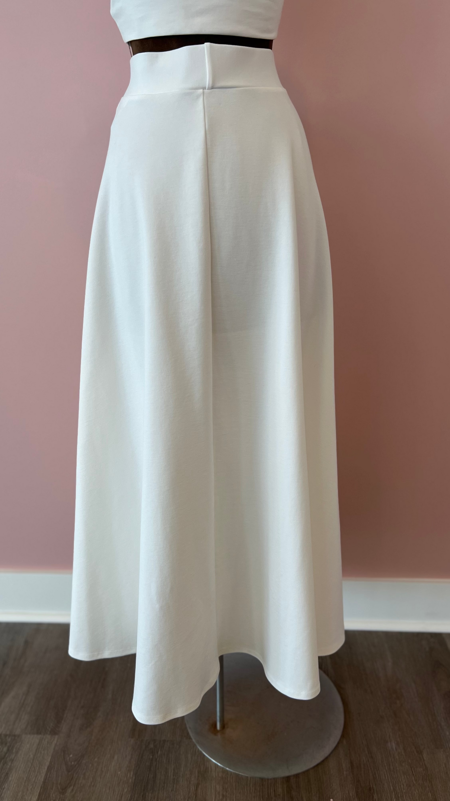 White skirt on a mannequin against a pink wall