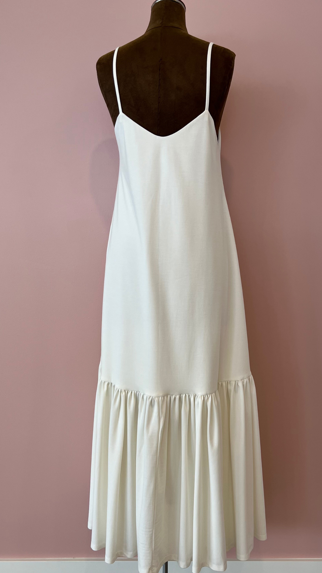 White slip dress on a mannequin against a pink background