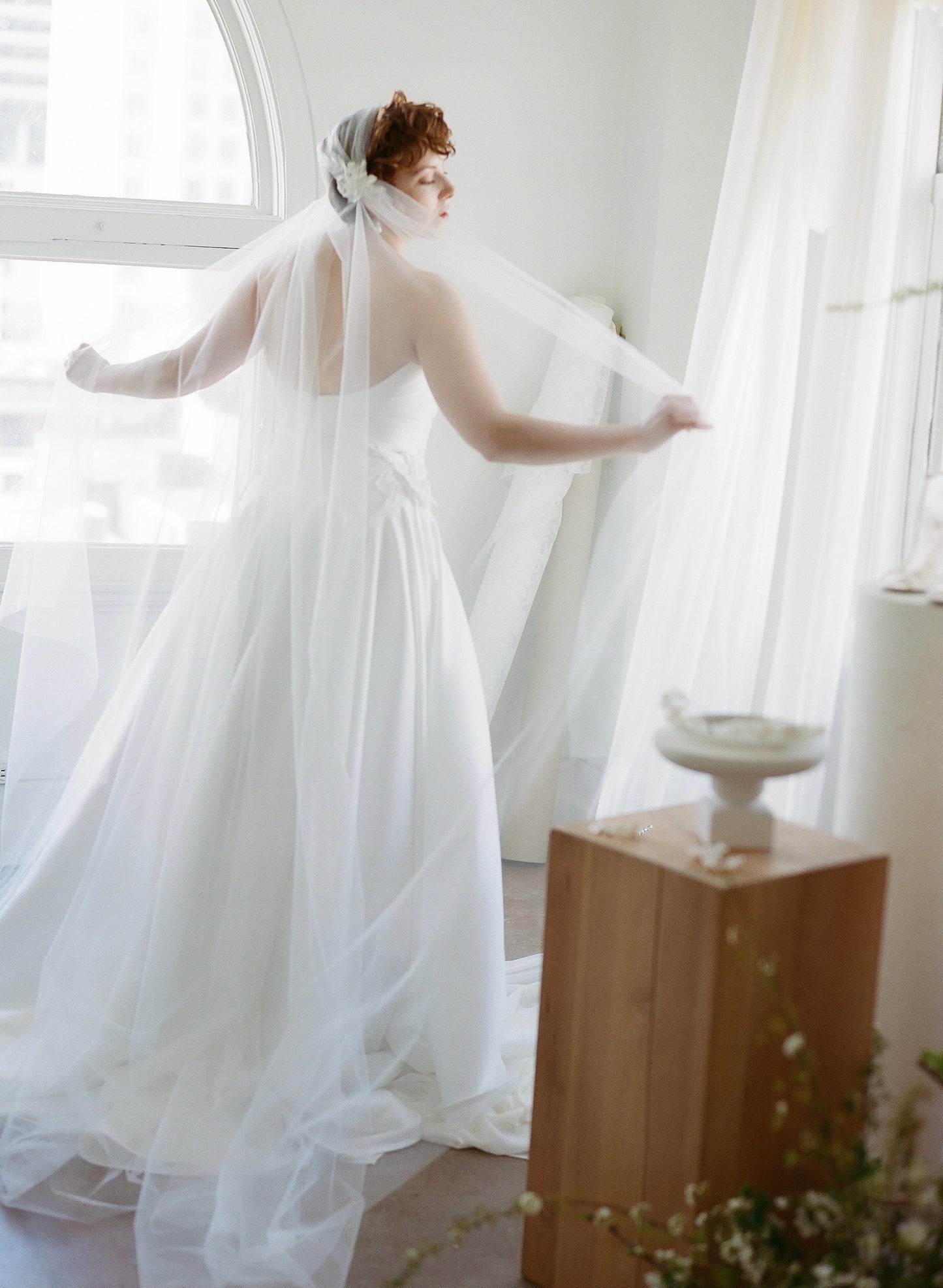 Bride in the mikado Lauralie dress, showing the optional applique on the hip, with a long juliet cathedral veil .