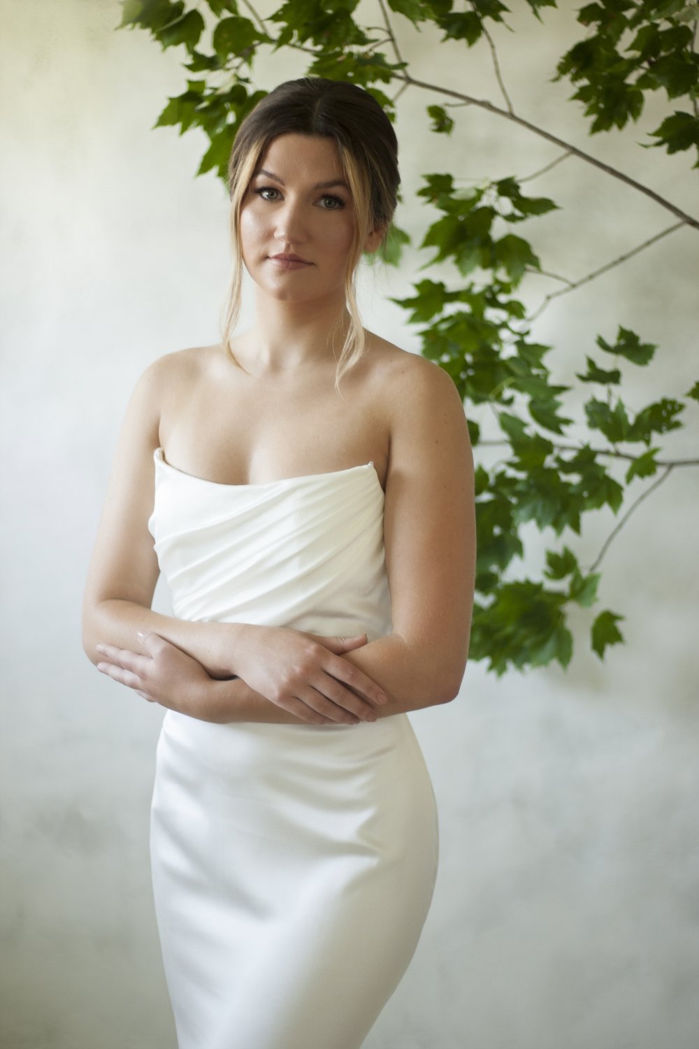A texture satin crepe gown featuring movement in a fit and flare profile with a delicate draped bodice