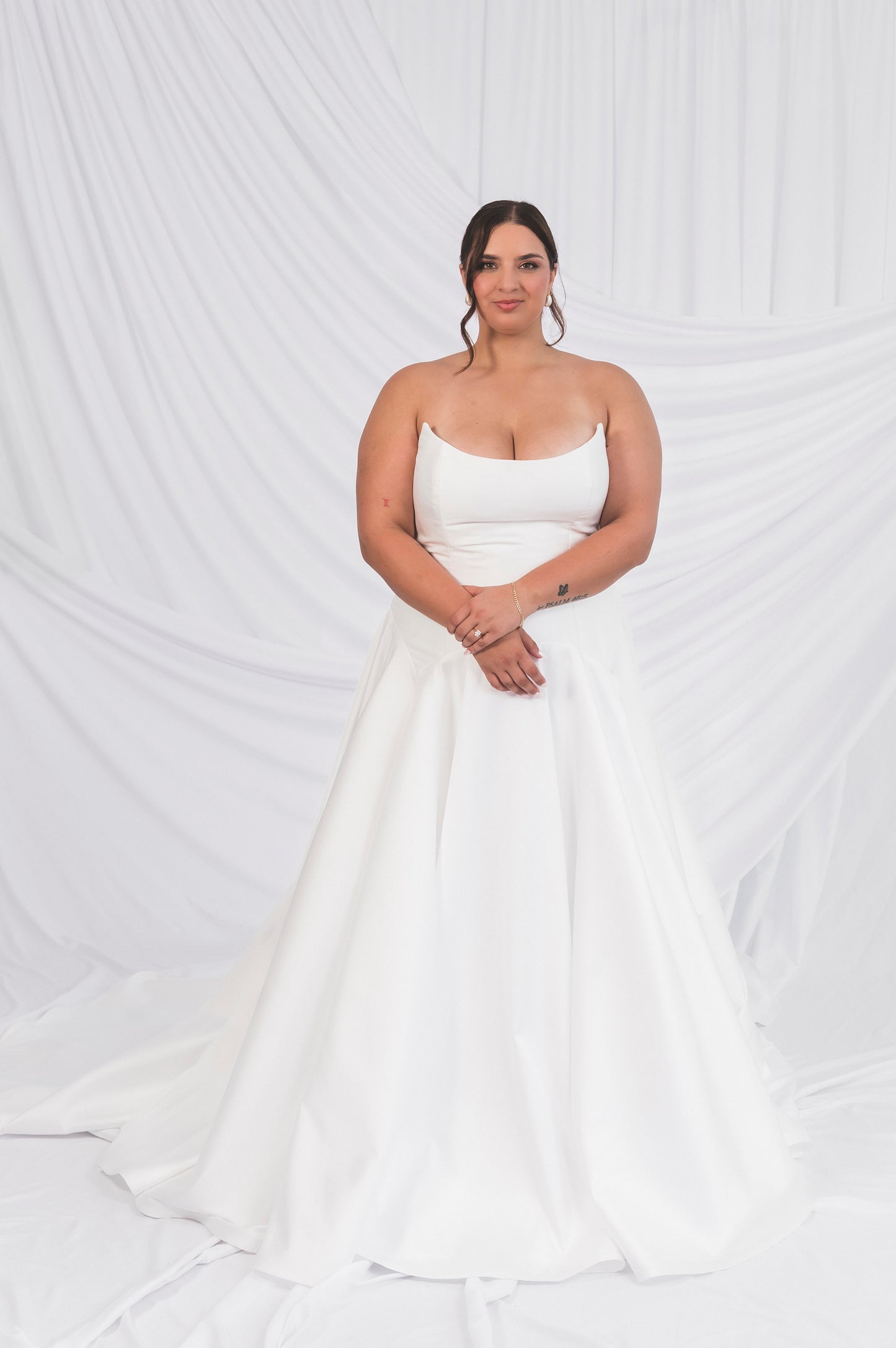Bride wearing the Lauralie gown, drop waist tear drop shape in silk white with a scoop cat eye neckline on the back of a draped background in Ottawa