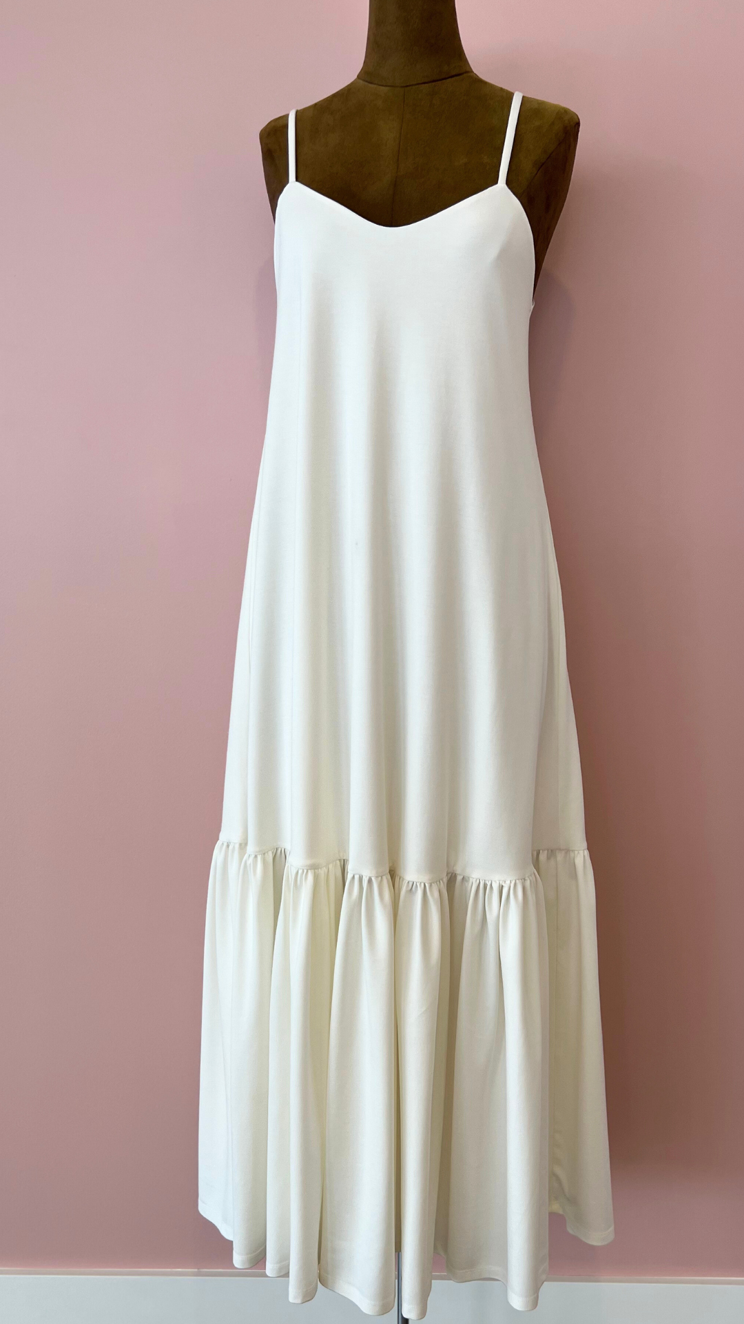 White dress on a mannequin against a pink background