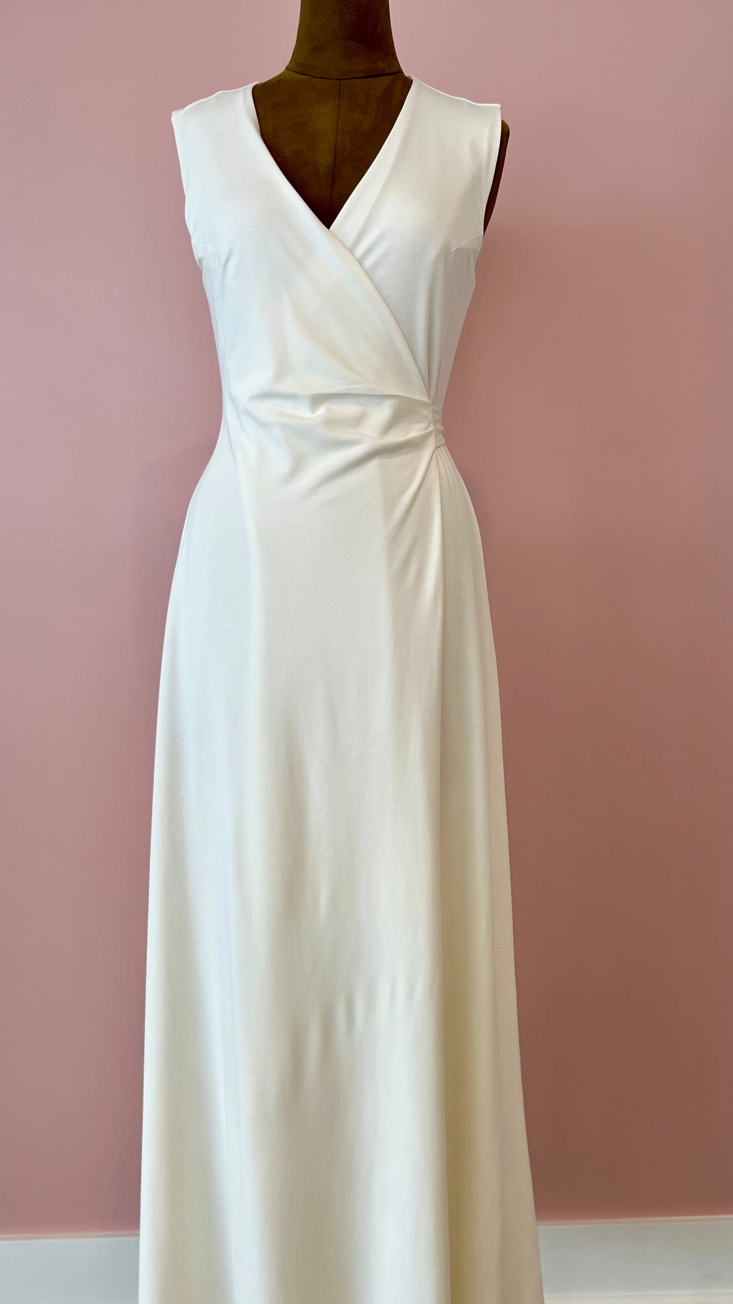 White evening gown on a mannequin against a pink wall