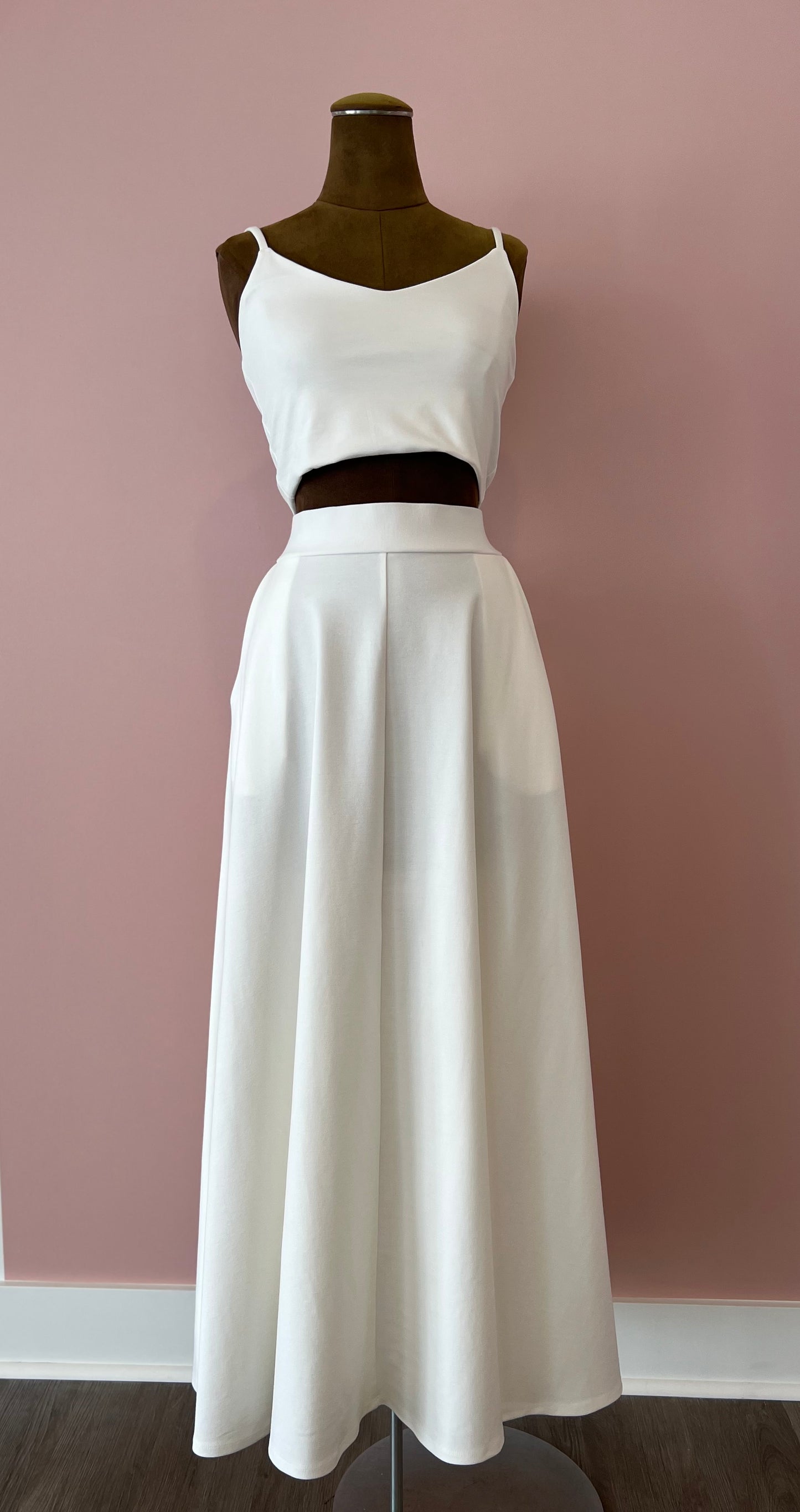 White two-piece dress on a mannequin against a pink wall.