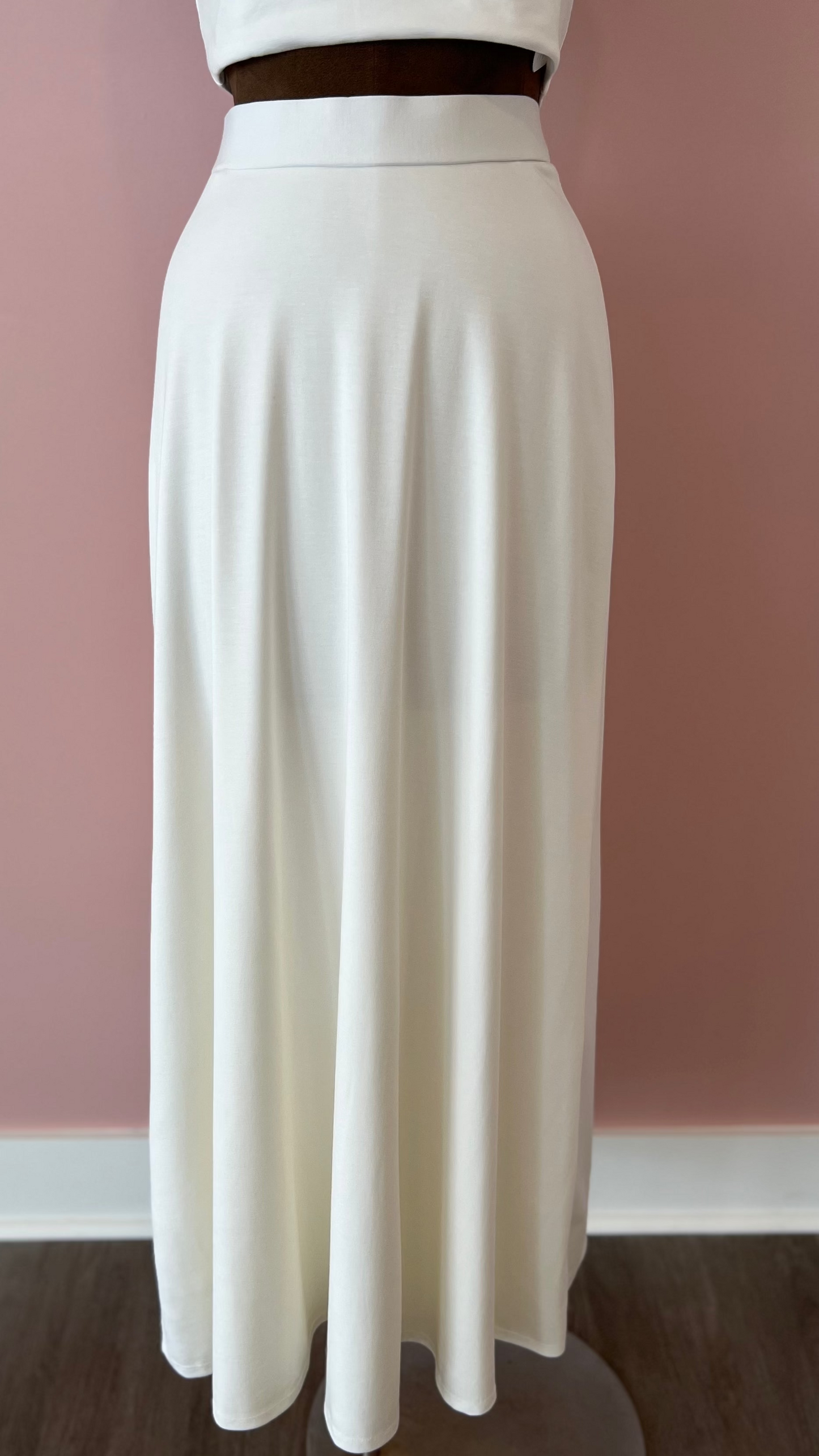 White skirt on a mannequin against a pink wall.