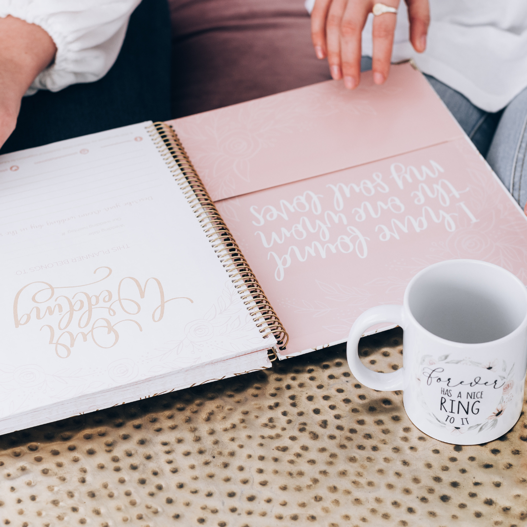 close look at a wedding planner beside a mug that reads "forever has a nice ring to it"