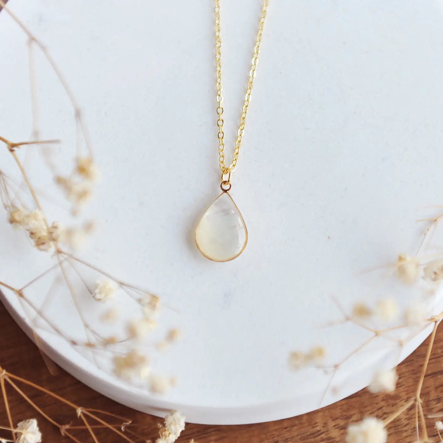 Mother of pearl necklace on a gold chain on a white and brown backdrop