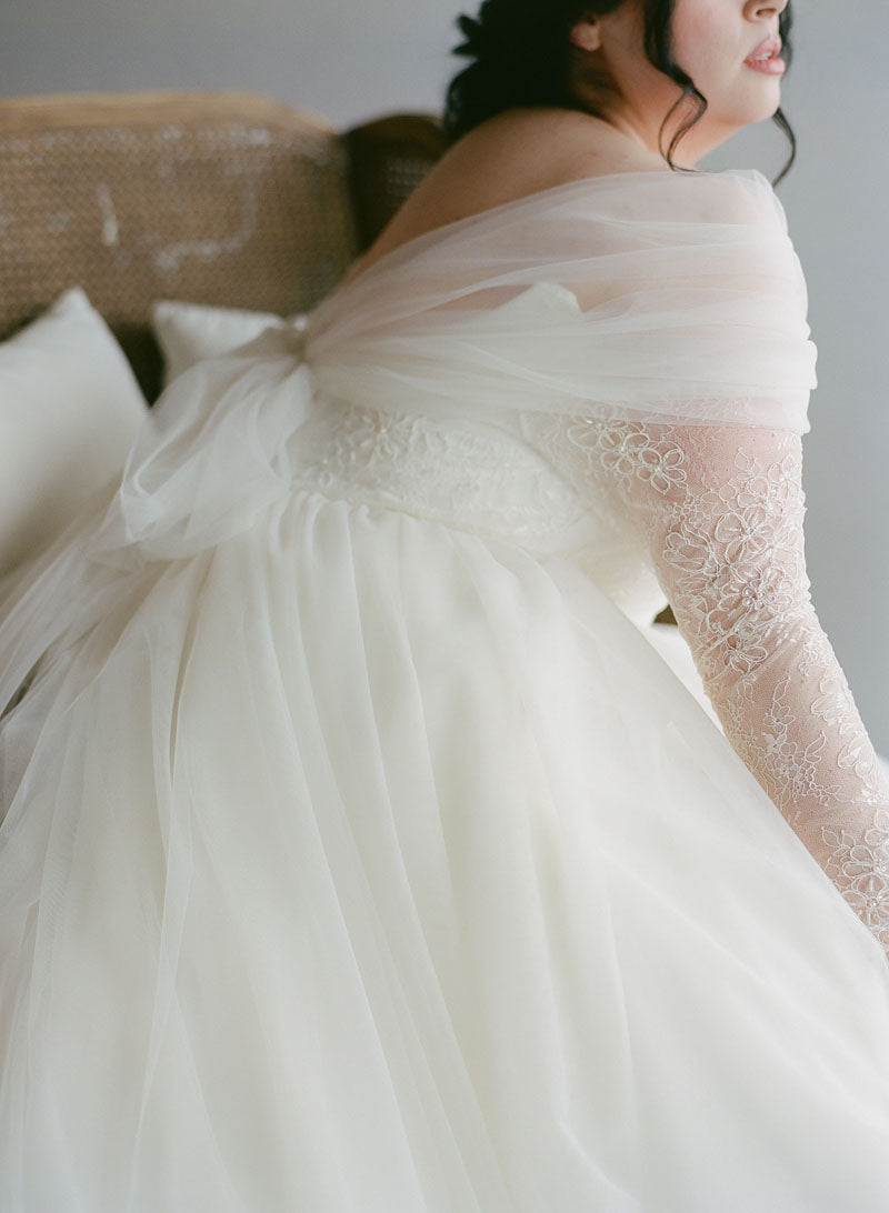 Woman wearing a white wedding dress with lace sleeves and a soft tulle skirt. Rose Topper, Kathryn Bass