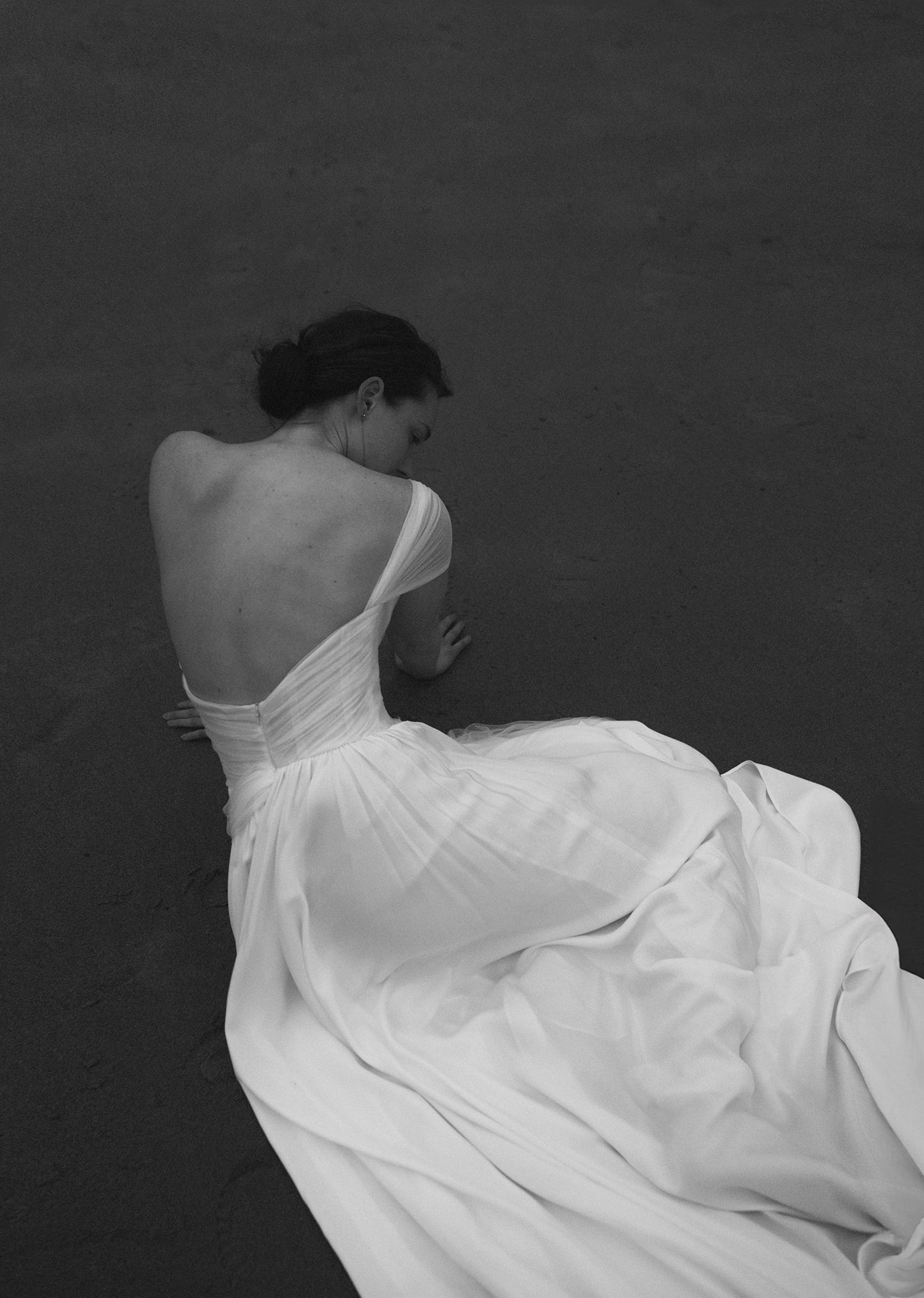 Woman in a white dress sitting on a dark floor