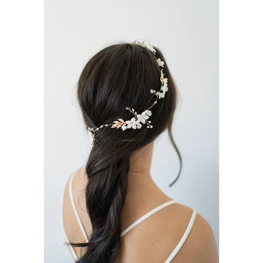 The Eliana hair vine with porcelain flowers, branches in a rose gold. Young woman wearing it in dark hair.