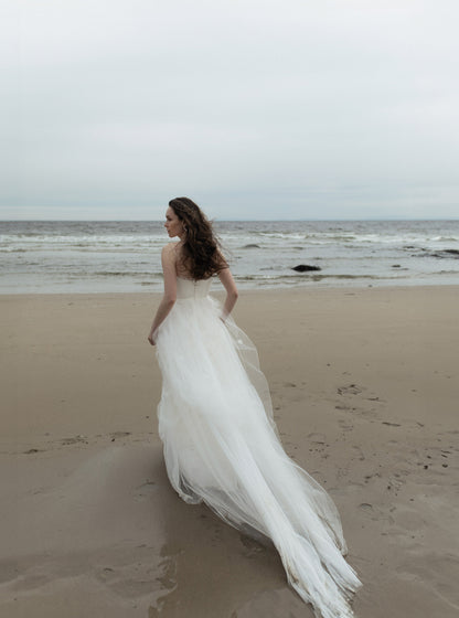 Woman in a white wedding dress standing on a beach