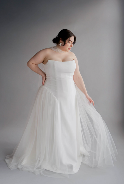Woman wearing a white strapless gown against a gray background