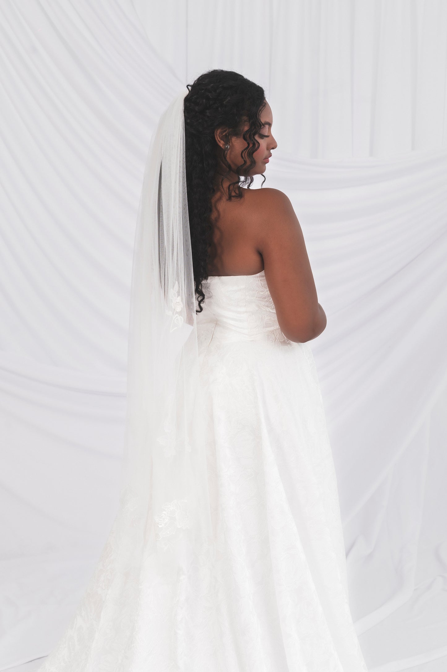 Back of Klein, aline jacquard wedding dress. Shown on a size 10 model with a matching fingertip veil
