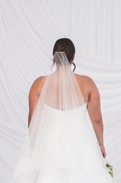 Showing the back of the Lauralie gown, featuring a high straight across mikado back and shown with a two tier simple cathedral length veil, matching silk white colour