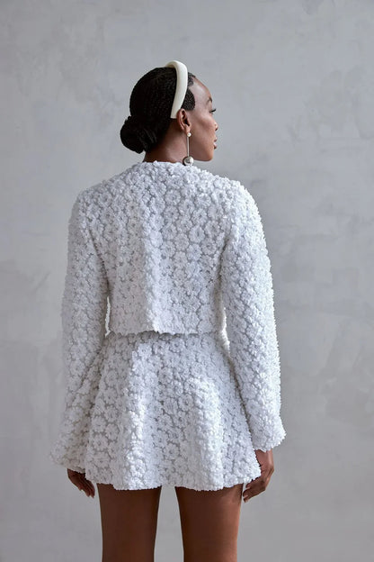 Woman wearing a white floral outfit against a gray background