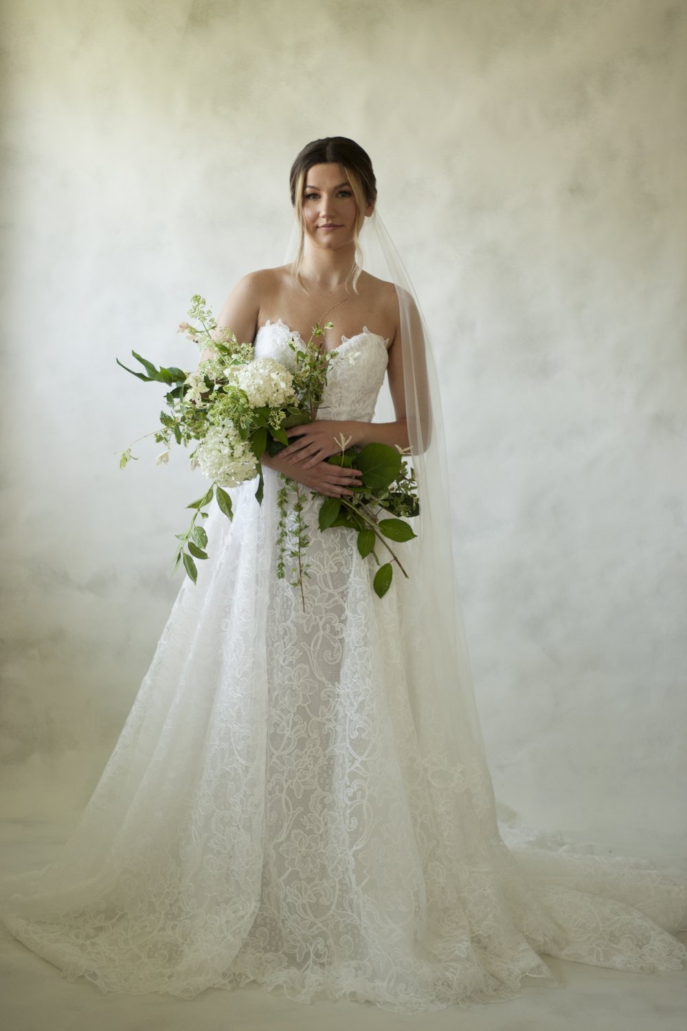 Constance is a stencil lace basque waistline gown featuring a corset bodice, deep plunge and button closure. The skirt finishes in a lace edge, showcasing the beautiful lace detailing. 