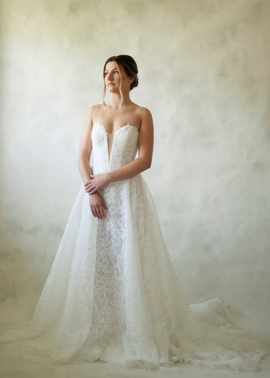 Constance is a stencil lace basque waistline gown featuring a corset bodice, deep plunge and button closure. The skirt finishes in a lace edge, showcasing the beautiful lace detailing. 