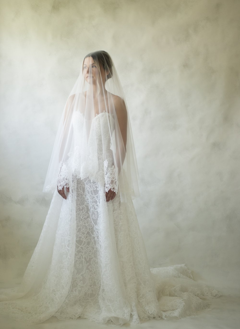 Constance is a stencil lace basque waistline gown featuring a corset bodice, deep plunge and button closure. The skirt finishes in a lace edge, showcasing the beautiful lace detailing. 
