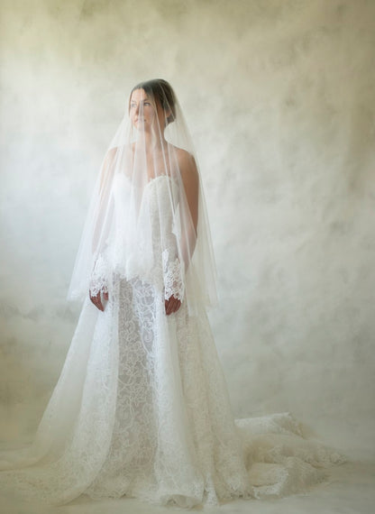 Constance is a stencil lace basque waistline gown featuring a corset bodice, deep plunge and button closure. The skirt finishes in a lace edge, showcasing the beautiful lace detailing. 