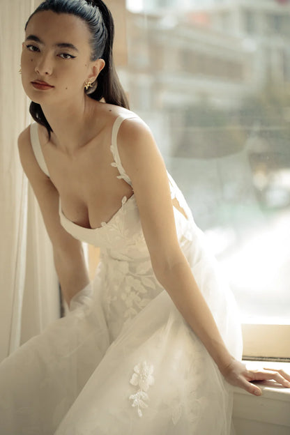 Gia, a flowy A-line gown with asymmetrical lace placement. A structured bodice with grosgrain straps features mesh paneling to enhance shape and style.