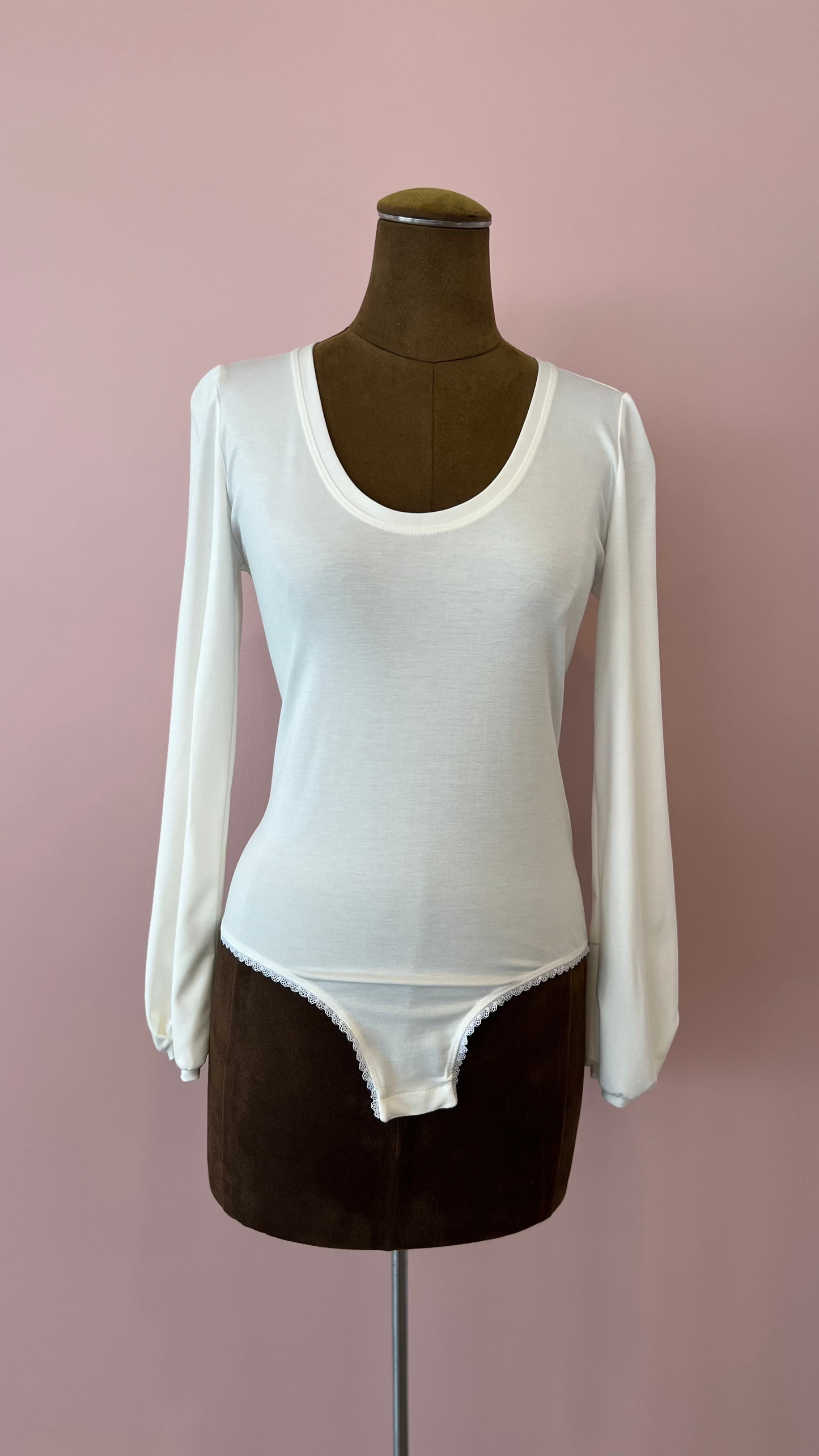 White long-sleeve bodysuit on a mannequin against a pink background