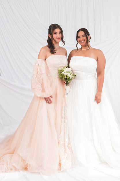 bride wearing blush ball gown gown with ballon sleeves and floral embroidery with a dramatic long train beside a plus size bride wearing a silk white tulle ballgown briar with large floral embroidery with a long train. 