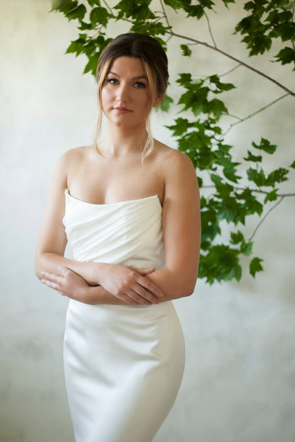 A texture satin crepe gown featuring movement in a fit and flare profile with a delicate draped bodice