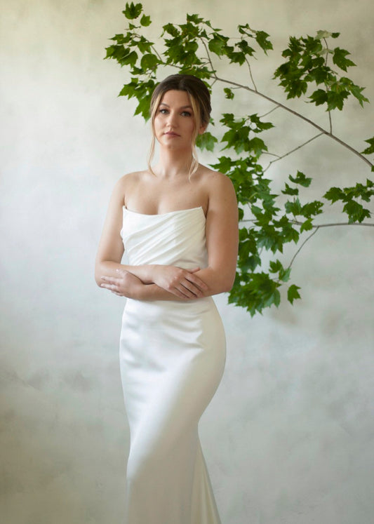 A texture satin crepe gown featuring movement in a fit and flare profile with a delicate draped bodice