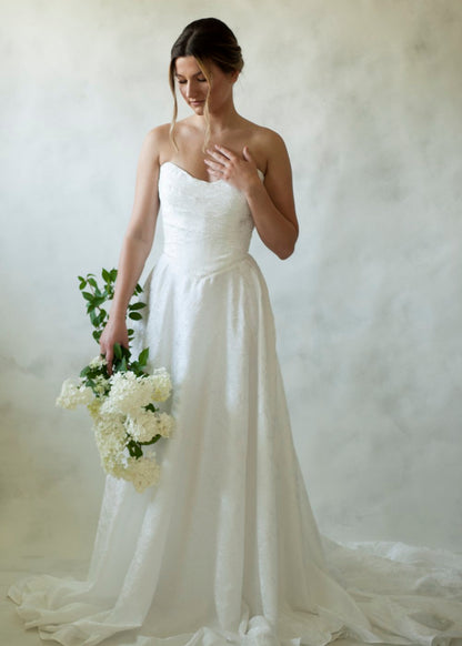 Meet Klein, stunning with a floral jacquard fabric and delicate full skirt. A soft scooped neckline and angular draped bodice create the beauty of Klein.