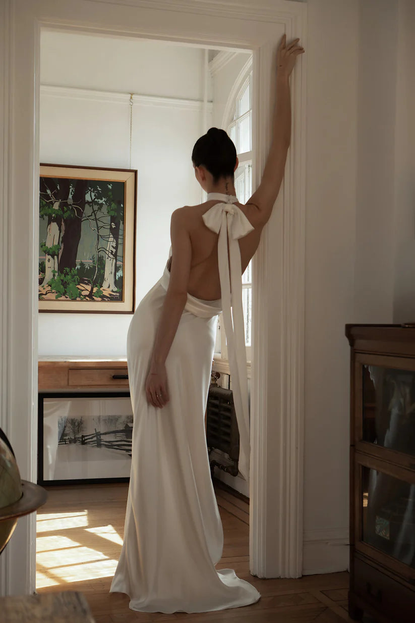 Laurene is a simple and sexy silk dress with halter neck. Adorned with pleats in the front, a leg slit and jaw dropping open back design. A detachable bow in the back finished off this timeless gown.