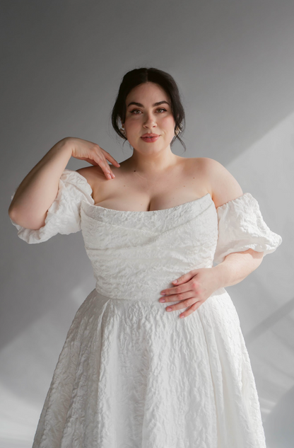Closeup of the Scooped Puffy Jacquard Neckline of the Lauren Gown. Plus size model with a puff removable sleeve