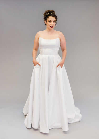 Front View of Poppy Clara, with a scooped soft cat neckline in silk white mikado, full skirt with buttons