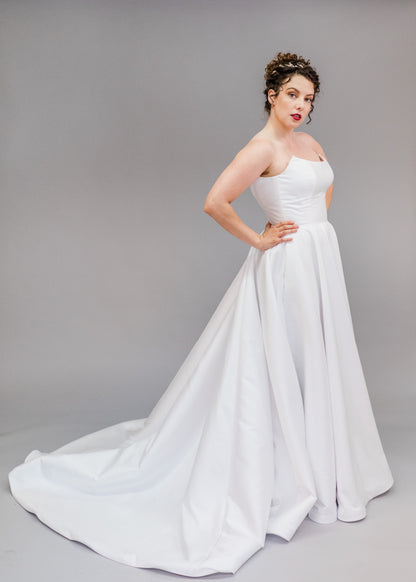 Full body side view of the poppy clara in white, strapless aline gown