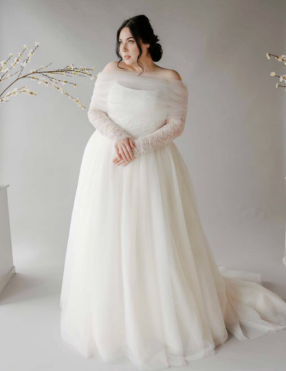 Woman wearing a white wedding dress with a long train against a plain background