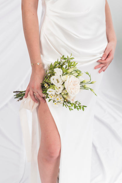 Closeup of the Laurene slit, high neck draped low back wedding dress, with a high high slit, no train and a sexy skirt