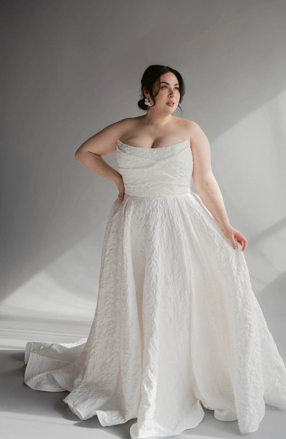 Woman wearing a white strapless gown against a neutral background