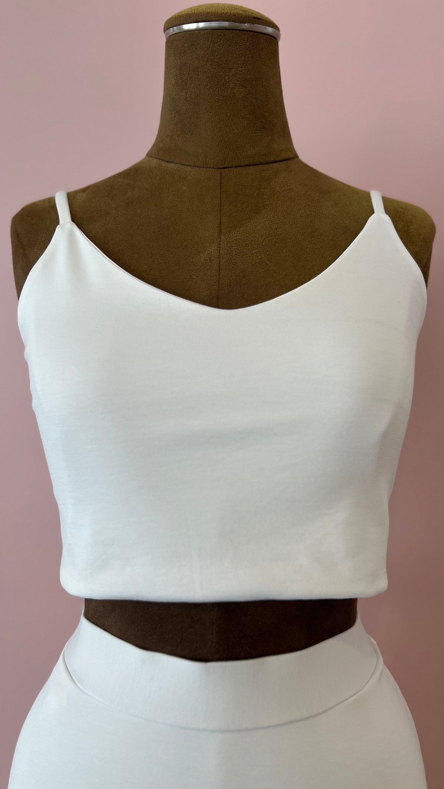 White crop top on a mannequin against a pink background