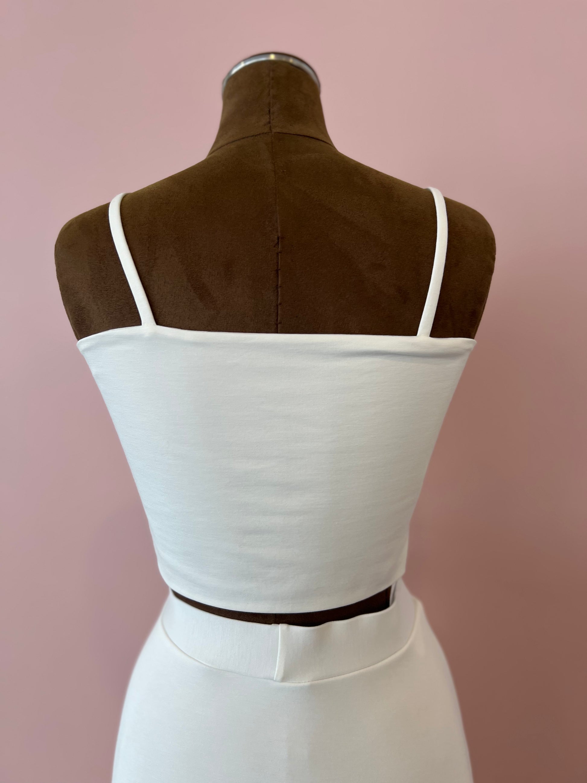 White dress on a mannequin against a pink background