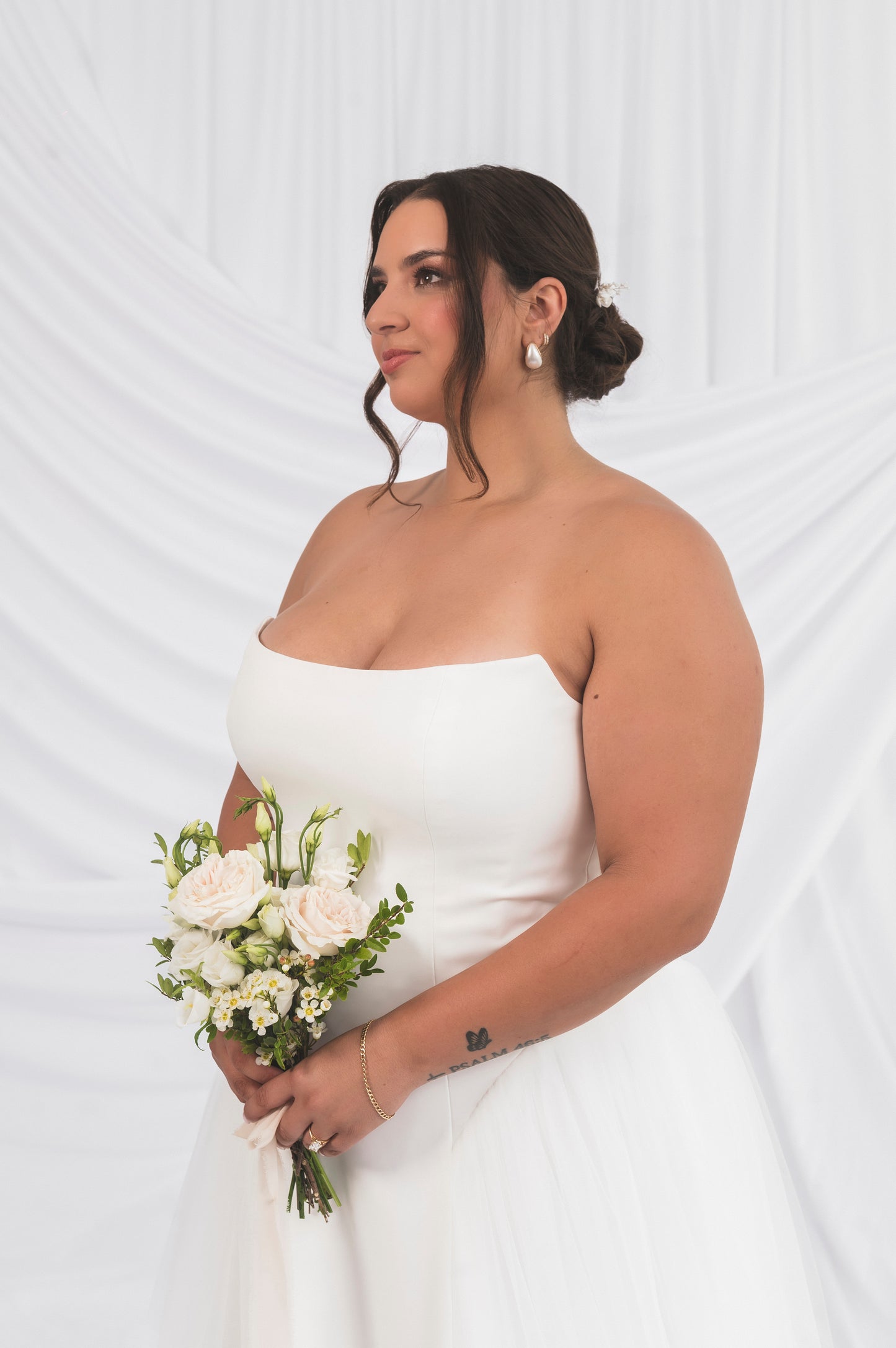 bride holding flowers in front of abigail gown bodice, white strapless column gown, cat eye neckline