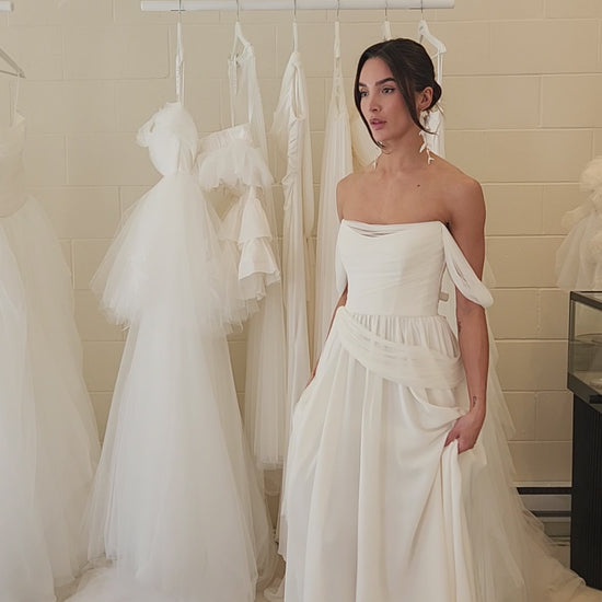 Model wearing the sora Aline gown from ouma. Soft scoop neckline, silk tulle draped features and removable sleevees 