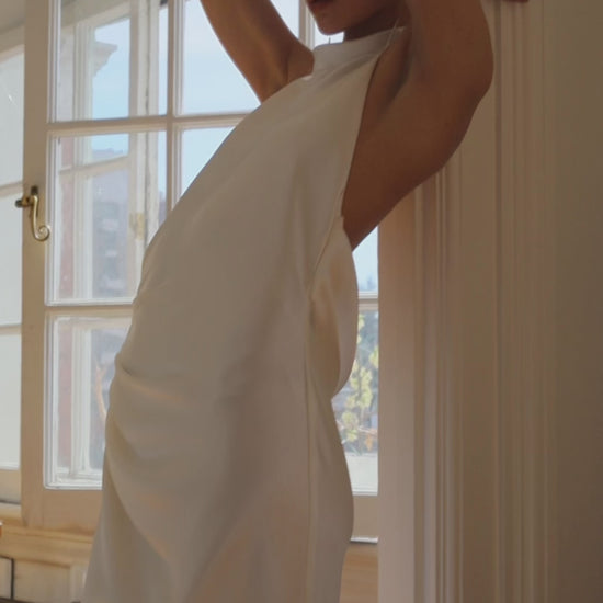 Closeup of the side of Laurene. The Laurene is a bias-cut silk blend dress featuring a high collar and open back. The dress has a relaxed fit due to the strategically placed pleats on the side with a leg opening. 

