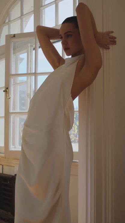 Closeup of the side of Laurene. The Laurene is a bias-cut silk blend dress featuring a high collar and open back. The dress has a relaxed fit due to the strategically placed pleats on the side with a leg opening. 

