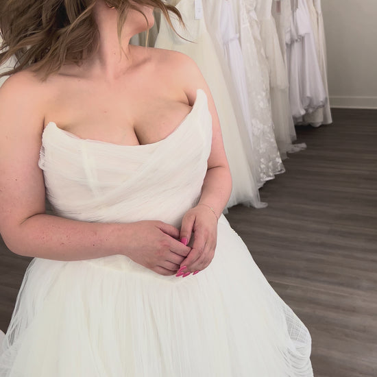 Closeup of Zara. Pleated Ballgown with a sharp cat eye neckline with a draped corset bodice and full asymmetrical skirt