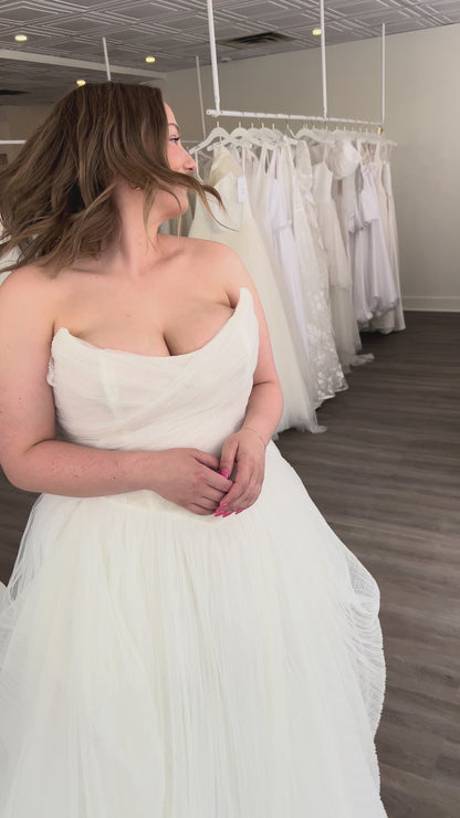 Closeup of Zara. Pleated Ballgown with a sharp cat eye neckline with a draped corset bodice and full asymmetrical skirt