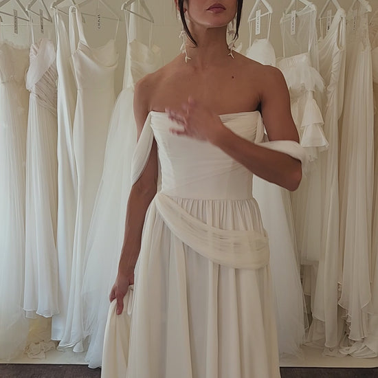 Model wearing the sora Aline gown from ouma. Soft scoop neckline, silk tulle draped features and removable sleevees 