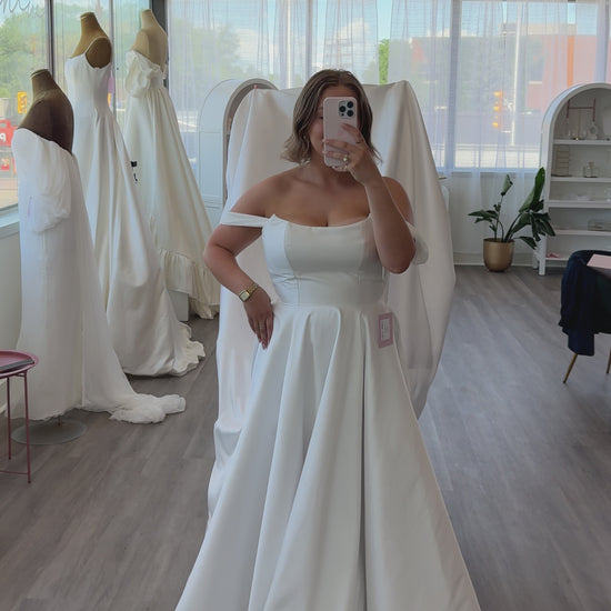 The train fluff of the Poppy Clara Dress, Shown in bridal size 10 with a soft cat eyeline fitted bodice with a mikado aline skirt